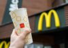 Hand holding McDonalds cup in front of sign