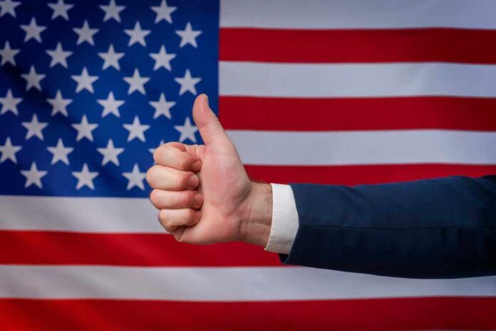 shutterstock_2207711983.jpg featured image Thumbs up in front of American flag background.