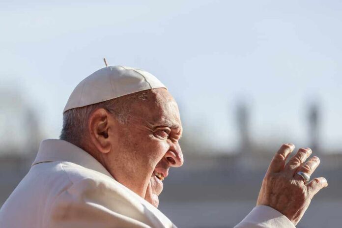 Pope Francis waving outdoors.