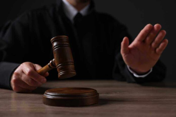shutterstock_2381854215.jpg featured image Judge holding gavel, hand raised in courtroom.