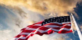 American flag waving under a cloudy sky.