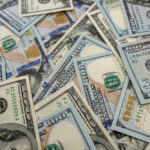 Scattered hundred dollar bills with Benjamin Franklin's portrait.