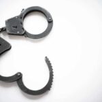 Open metal handcuffs on white background.