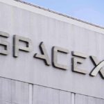 SpaceX building logo against blue sky.