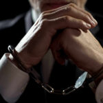 WATCH: Democrat Senator FORCIBLY Removed – HANDCUFFED! Handcuffed person in suit, hands clasped together.