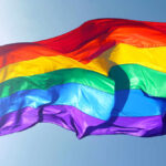 Rainbow flag waving against clear blue sky