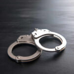 Metal handcuffs on a dark textured surface.