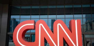 Red CNN logo in front of glass building.