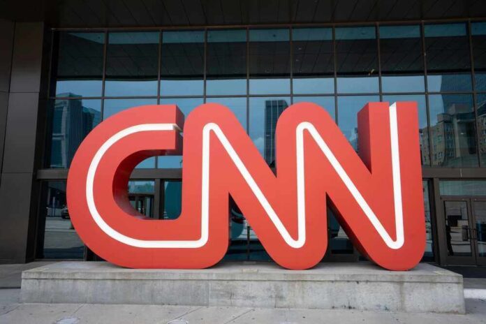 Red CNN logo in front of glass building.