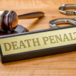 Gavel handcuffs and death penalty sign on table