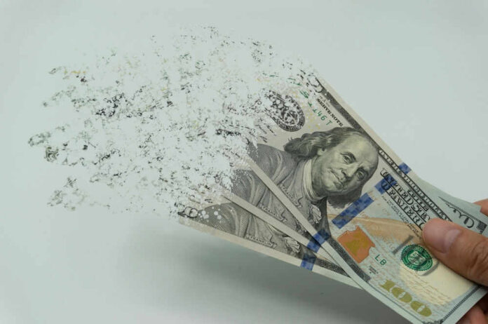 shutterstock_2122253927.jpg Hundred dollar bills disintegrating in hand