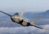 F-35 fighter jet flying above clouds with mountains in the background