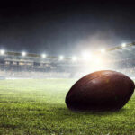 Football on field in illuminated stadium at night