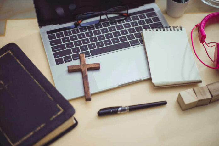 Bible, cross, laptop, notebook, pen, and headphones