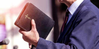 Man holding a Bible during a speech or presentation