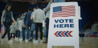 People in line next to Vote Here sign