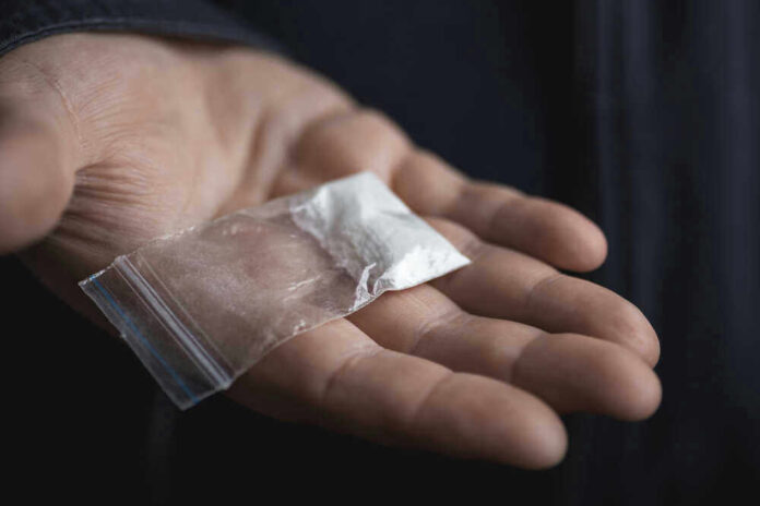 Hand holding small bag of white powder
