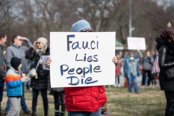 Person holding sign reading Fauci Lies People Die