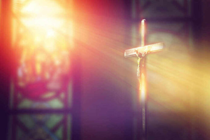 Crucifix with sunlight, stained glass window in background.
