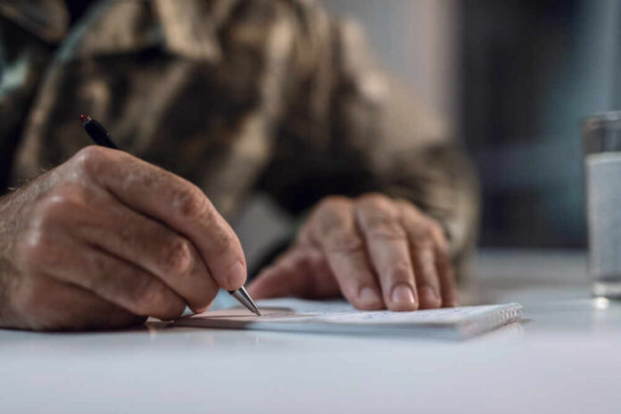 A hand writing on a notepad with a pen