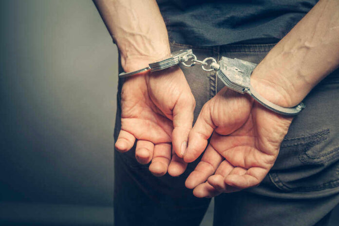 Person with handcuffs behind their back.