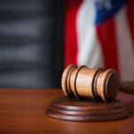 Judge Torpedoes GOP Stronghold A wooden gavel resting on a sound block with an American flag in the background