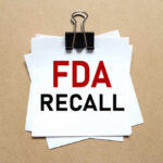 FDA ESCALATES Recall — DEATH WARNING A notice labeled 'FDA RECALL' clipped to white papers on a brown background