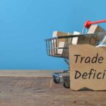 Trade Deficit EXPLODES! A shopping cart with wooden blocks and a sign reading 'Trade Deficit'