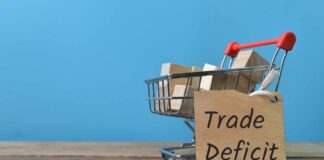 A shopping cart with wooden blocks and a sign reading 'Trade Deficit'