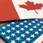 Trump Threatens Canada Canadian and American flags overlapping on a surface