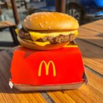 McDonald’s CAUGHT Using Cheaper Meat Substitutes? A cheeseburger from McDonald's placed on a red box on a wooden table