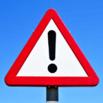 IGNORED Warnings Lead to 8 Being Killed A triangular warning sign with an exclamation mark against a blue sky