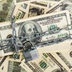 Trump FREEZES Billions — Liberal States STUNNED A stack of hundred dollar bills secured with a chain and padlock