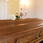 Music Star DEAD at 50 — Mystery Deepens A wooden casket with a white rose placed on top in a solemn setting