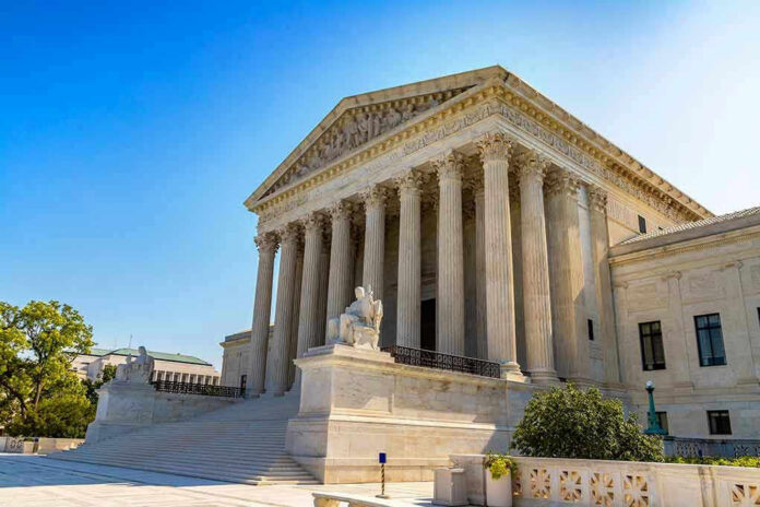 Stone building with columns and statues, clear blue sky.