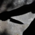 Shadow of a hand holding a knife on a textured surface