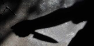 Shadow of a hand holding a knife on a textured surface
