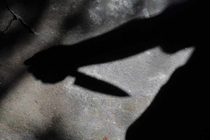 Shadow of a hand holding a knife on a textured surface
