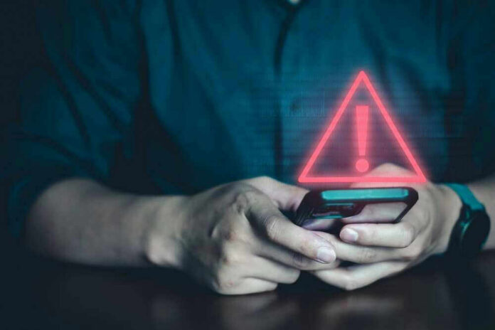 Person holding phone with warning symbol displayed.
