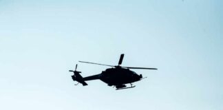Silhouette of a helicopter flying against a light sky
