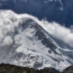 Snow-covered mountain peak partially obscured by clouds