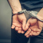 Person in handcuffs, hands behind their back.