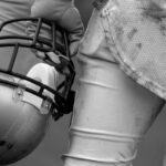 Was This EX-NFL Star Killed By a Serial Killer? Football player holding helmet, dirty uniform close-up.