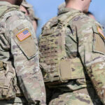 Army Ups Age Limit In Bombshell Announcement Soldiers in camouflage uniforms with American flag patches.