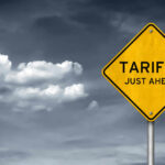 Yellow sign saying tariffs just ahead cloudy sky