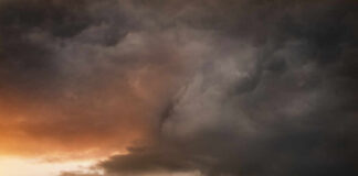 A tornado forming under dark storm clouds at sunset