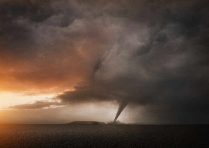 A tornado forming under dark storm clouds at sunset