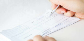 Person signing a check on a white background.