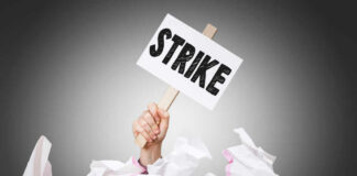 Hand holding strike sign amid crumpled paper pile