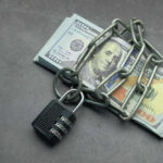 A stack of cash secured with a chain and padlock